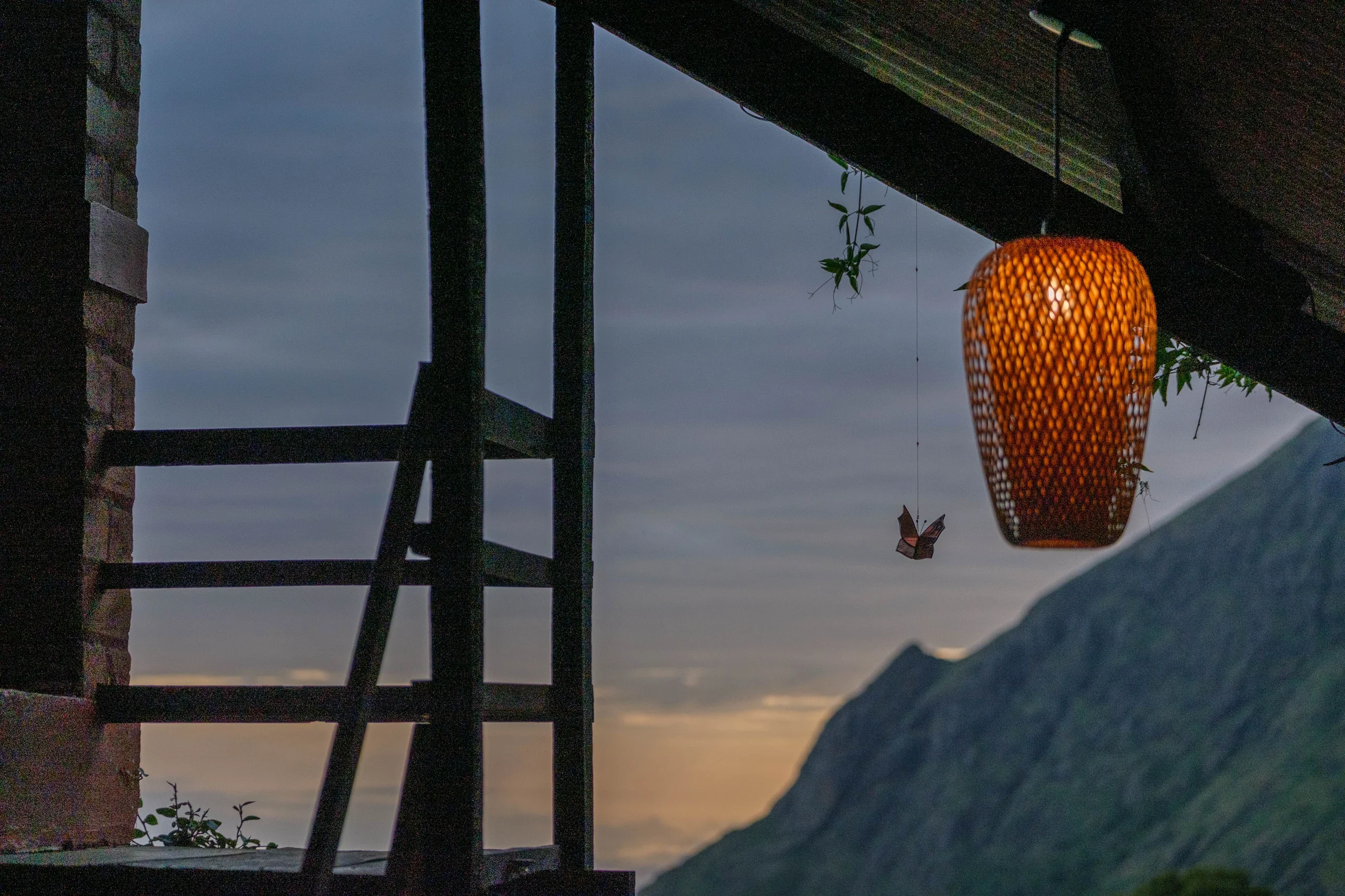 A glowing woven lantern hanging above the mountain-facing verandah