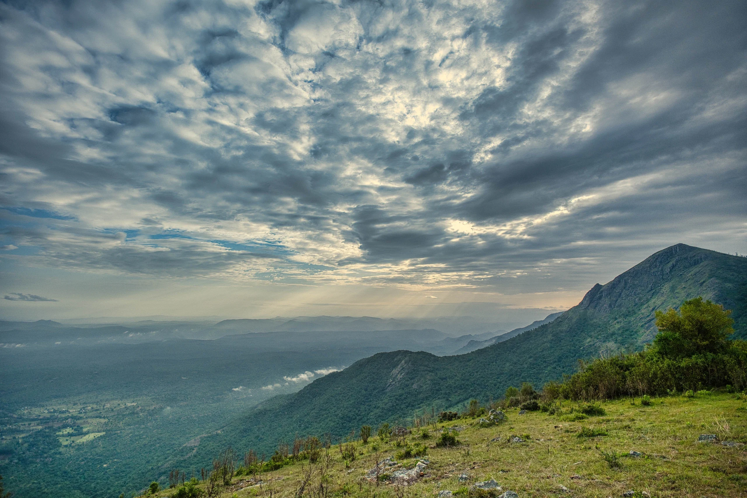 An expansive green Nilgiri valley beneath a dramatic cloud-filled sky