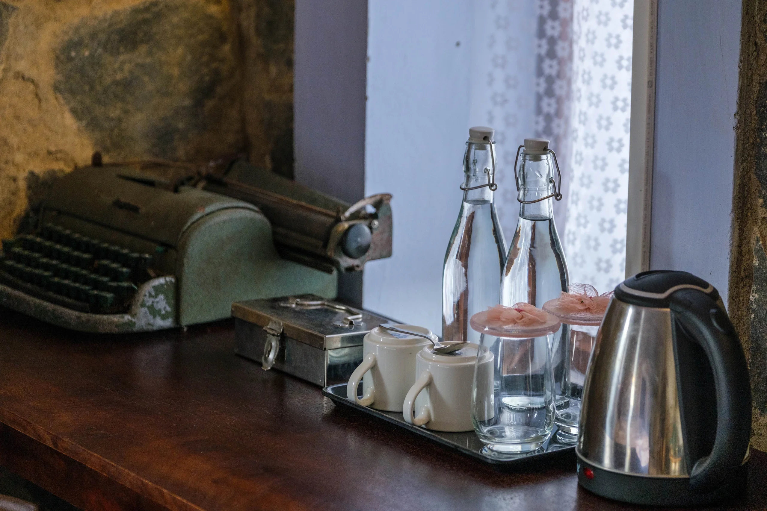 Tea cups, glass water bottles, and a kettle on a wooden table at Hullathy
