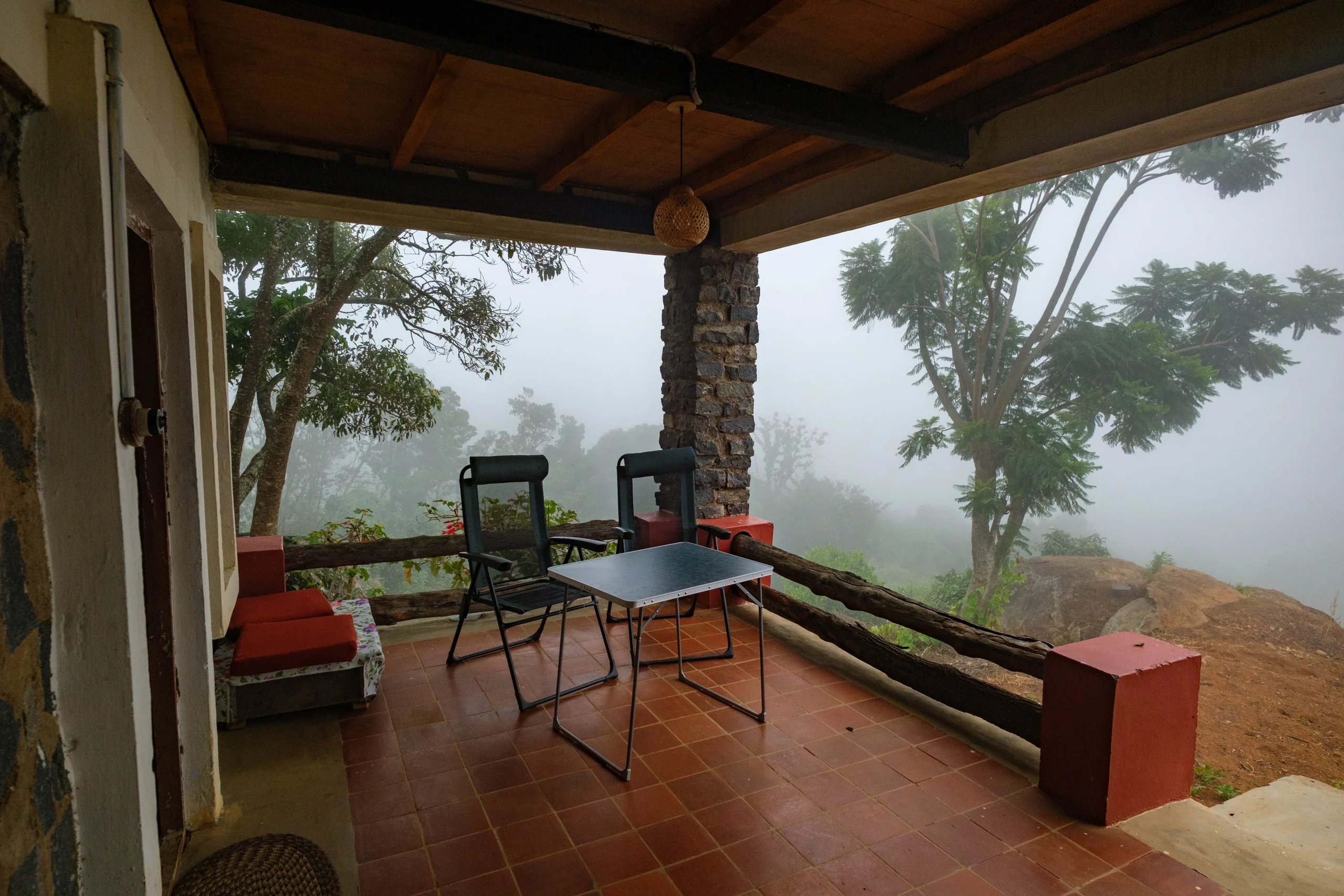 A verandah with chairs and a table looking into the mountain mist
