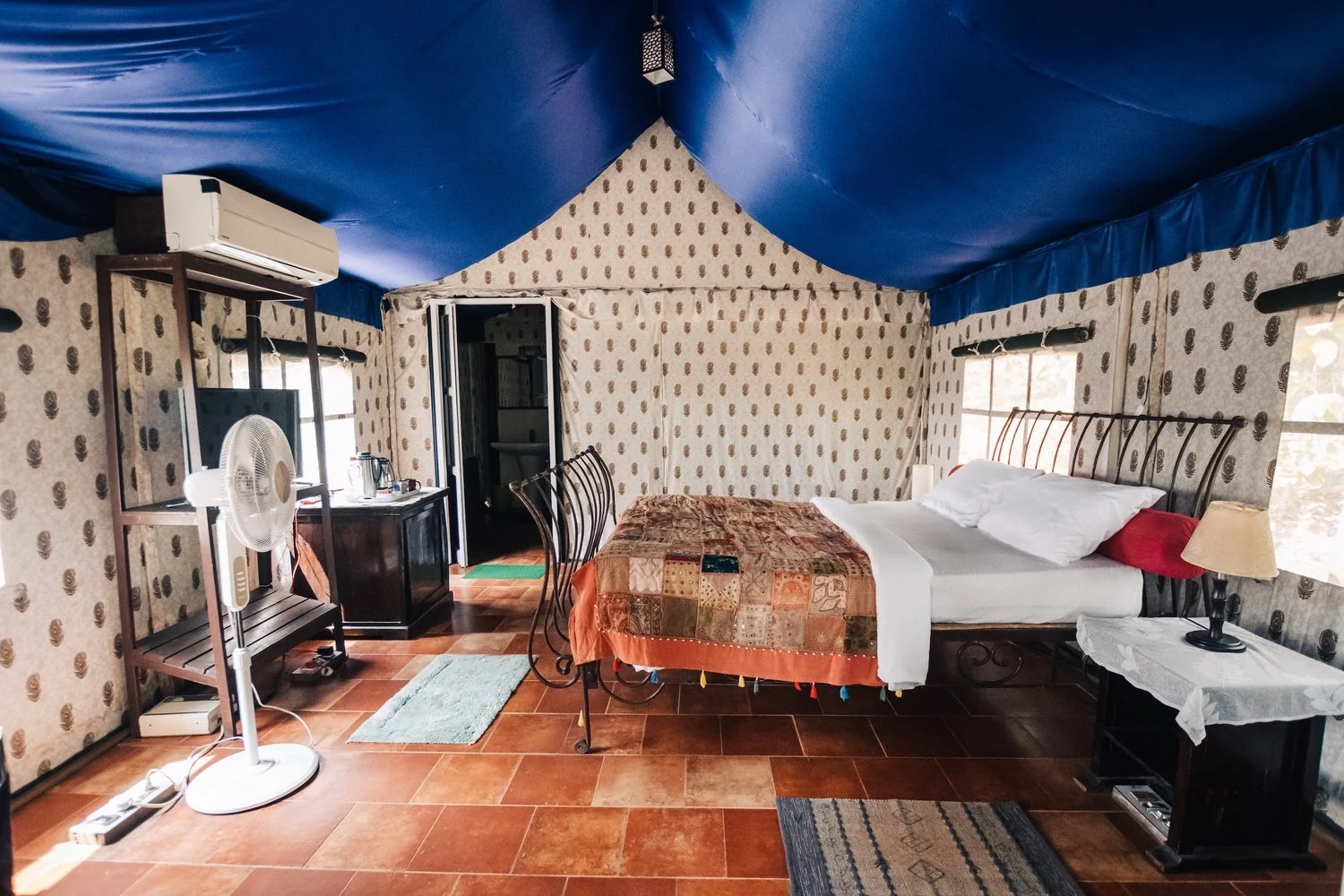A tent-style room with a blue canopy ceiling and patchwork bedspread