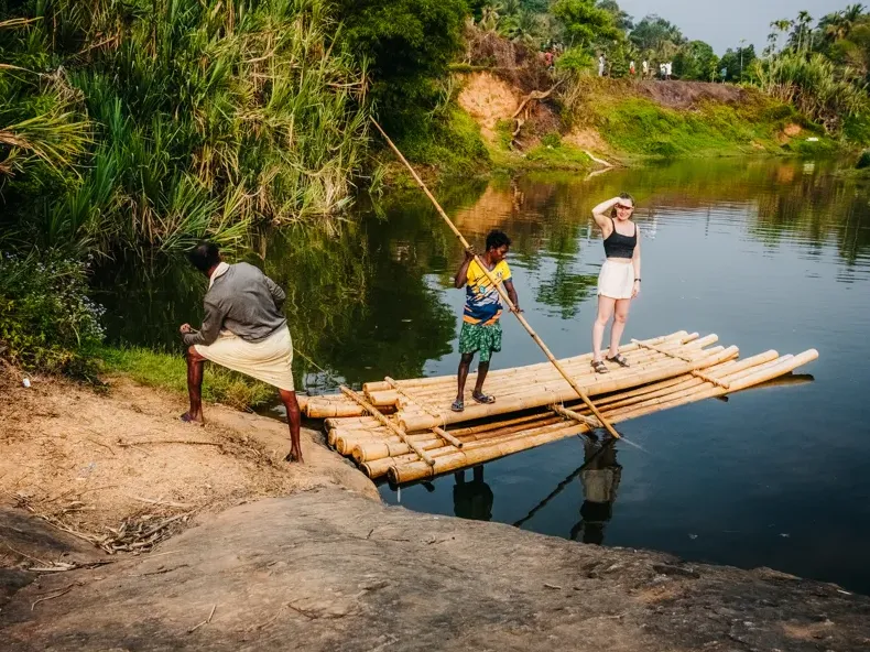 Guests crossing a handmade bamboo bridge over a hill stream